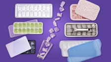 six ice cube trays and a glass spilling ice