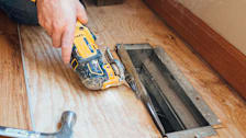 detail of handing hold oscillating multi-tool to cut opening through floor for heat register