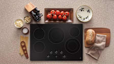GE JP5030SJSS Smooth top cooktop surrounded by ingredients to make pasta.