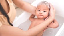 Baby is being bathed and shampooed by his mother