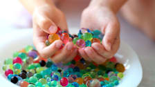 Children's hands holding Orbeez water beads.