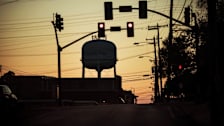 A water tower is framed by electrical wires and traffic lights at sunset in Philadelphia, Miss.