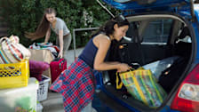 2 people unloading trunk of car filled with college dormitory items