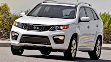 white 2012 Kia Sorento on road with sidewalk and bushes in background