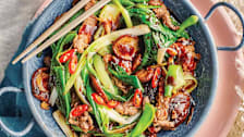 overhead view of bowl of beef stir fry with scallions, red chilis, and shiitake mushrooms