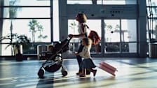 Family walking through airport with baby luggage and gear.