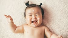 a smiling baby with skin cream on her face