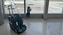 a toddler at an airport next to a suitcase and car seat