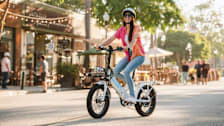 person riding Lectric 3.0 ebike through commerical neighborhood with businesses in the background