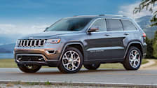 grey Jeep Grand Cherokee with trees and mountains behind it
