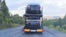 Cars stacked in a transport vehicle on the road.
