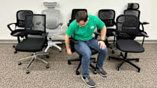 person wearing green Consumer Reports shirt, sitting in office chair with 7 other office chairs surrounding them