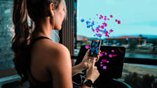 Woman using exercise machine while uploading data.
