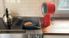 kitchen counter and range with salmon cooking in pan and Airhood Range Hood
