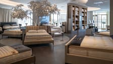 Saatva Mattress showroom in Paramus, NJ showing several beds with different mattresses and a display case with pillows