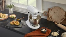 white KitchenAid K45SSWH stand mixer with dough hook, on countertop with pretzel dough in mixer and pretzels on counter