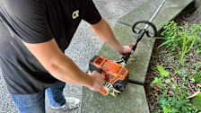 detail of person wearing Consumer Reports shirt starting gas powered string trimmer