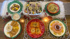 overhead view showing the seven dishes served during the Feast of Seven Fishes with lit candles and other holiday decor