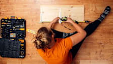Woman drilling bracket to a shelf at home with toolkit