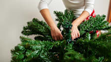 close up of person setting up artificial Christmas tree, adjusting branches on tree to section of tree