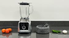 a blender, a Molcajete and ingredients for salsa on a kitchen counter top