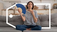 A woman sitting on the couch is fanning herself with a deal tag surrounding her.