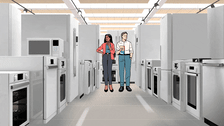 Two people are walking through an appliance showroom aisle lined with ovens, ranges, refrigerators, dishwashers, and microwaves.