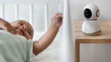A baby in a crib next to a Maxi-Cosi See Pro 360 Baby Monitor.