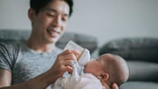 Dad feeding baby with a bottle on a couch
