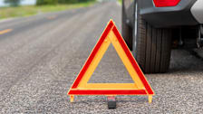 close up of safety triangle on road with portion of car blurred in the background