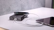 Mophie Powerstation Pro AC 27,000mAh 100W portable charger charging a phone and tablet on a table.