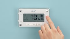hand adjusting setting on Orbit Clear Comfort 83521 Thermostat on light blue wall