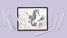 overhead view of tablet showing drawing of flowers and sea horses with 8 different styluses next to the tablet