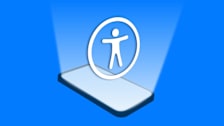 Illustration showing a cell phone laying on a surface with Apple's symbol for accessibility shining out of the screen.