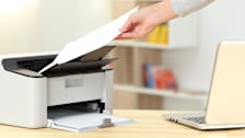 Close up of a woman hand catching a document from a printer on a desk at home