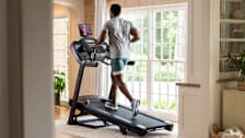 A man running on a Horizon 7.0 AT treadmill in a home.
