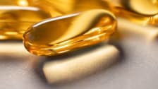 close up of fish oil supplement pill with strong shadow and additional pills blurred in the background