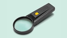 handheld magnifier with a light on a light green background