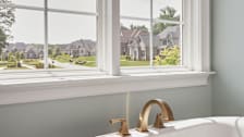JELD-WEN V-4500 Series replacement window in bathroom with bathtub in foreground and houses outside the window