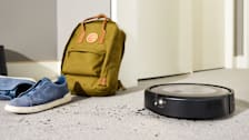 iRobot Roomba Combo j9+ on carpet with dirt, backpack, and sneakers in background