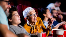 People clearly hearing a movie at a theater while eating popcorn