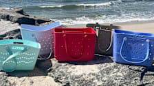 Five rubber beach totes on a beach