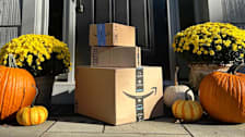 Amazon packages on front door step with pumpkins and mum plants