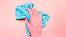 A hand wearing a cleaning glove holding a microfiber cloth.