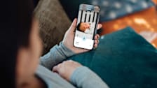Parent looking at baby sleeping on phone through baby monitor