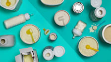 A number of liquid and powder baby formulas seen from above split between a lighter and darker shade of teal.