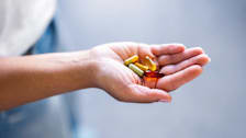 hand holding various supplements with grey background