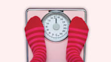 overhead view of feet with pink and red striped socks on scale that says "uh oh!", pink background