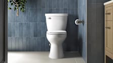 Kohler Cimarron Rev 360 K-31668 toilet seen in a blue-tiled bathroom.