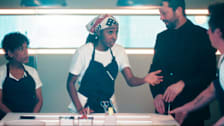 A tense kitchen scene from The Bear featuring Liza Colón-Zayas, Ayo Edebiri, Ebon Moss-Bachrach, and Jeremy Allen White. Ayo Edebiri's character gestures emphatically while speaking, as the others look on closely in a modern, restaurant-kitchen interior.